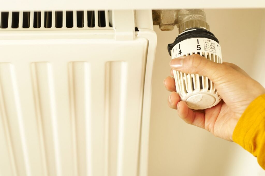 Main réglant un thermostat de chauffage pour économiser de l'énergie